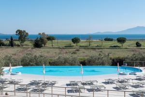 una grande piscina con sedie a sdraio e l'oceano di Pigna Felice Talamone a Talamone