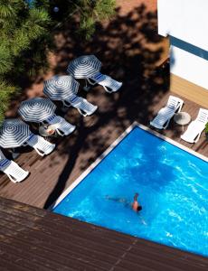 a person swimming in a swimming pool next to chairs and a swimming pool at Buxus Villas Shekvetili in Shekvetili
