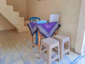 uma mesa com um portátil com dois bancos em OYO 93902 Guest House Pahlawan Syariah em Kotabumi