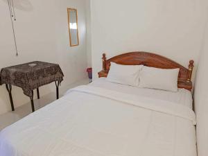 1 dormitorio con cama blanca y mesa en OYO 93902 Guest House Pahlawan Syariah, en Kotabumi