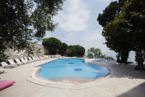 a large swimming pool with lounge chairs and the ocean at Kırtay Hotel Erdek in Erdek