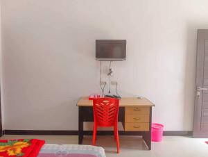 una silla roja sentada frente a un escritorio en OYO 93902 Guest House Pahlawan Syariah, en Kotabumi