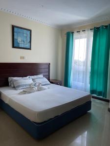 a bedroom with a large bed with blue curtains at Sunrise Resort 1BR Apartment in Nyali +11 photos