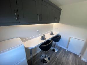 a kitchen with black cabinets and two stools at Tummel View Pitlochry in Pitlochry +14 photos
