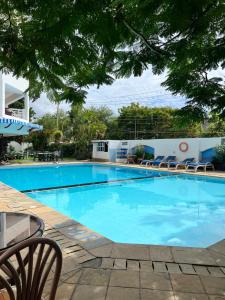 a large blue swimming pool with chairs and trees at Sunrise Resort 1BR Apartment in Nyali