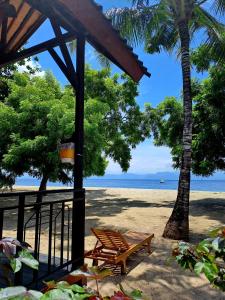 a beach with a bench and palm trees and the ocean at Beach House Penida in Nusa Penida