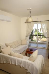 a living room with a white couch and a table at Sunset Green 01 in Paphos City