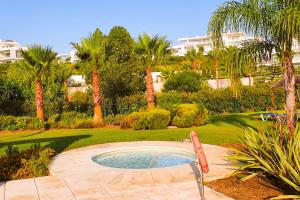 a pool with a chair in a garden with palm trees at Luxury Penthouse Alcazaba Lagoon 622 EHHouse in Estepona