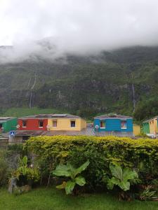 a row of colorful houses in front of a mountain at Cascades de la mare à poule d'eau in Salazie