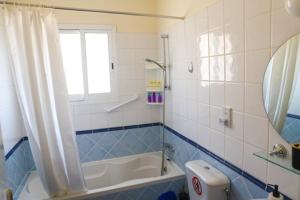 baño azul y blanco con bañera y ventana en Sunset Green 01 en Pafos