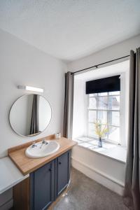 a bathroom with a sink and a mirror and a window at The Beaufort Hotel in Chepstow