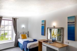 Schlafzimmer mit einem Bett und einem Schreibtisch mit einem Spiegel in der Unterkunft The Beaufort Hotel in Chepstow