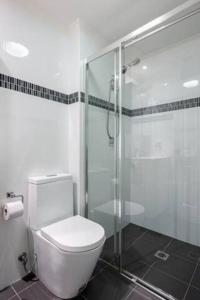 a bathroom with a toilet and a glass shower at Convenient Studio With Courtyard in Sydney