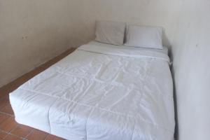 uma cama com lençóis brancos e almofadas num quarto em SPOT ON 93917 Homestay Adreena Syariah em Purwokerto