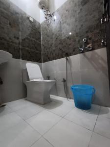a bathroom with a toilet and a shower and a blue bucket at Hotel JP Inn in Lucknow