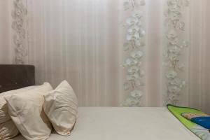 a bed with white pillows and a white curtain at OYO 93918 Wisma Tulip 