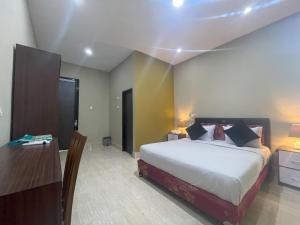 a bedroom with a bed and a table and a desk at Aislah Edotel Lombok in Sakra