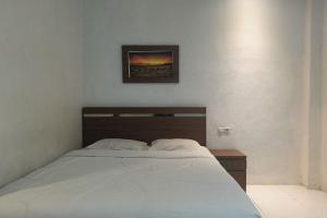 um quarto com uma cama e uma fotografia na parede em OYO 93929 Erbee Inn em Makassar