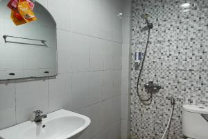 uma casa de banho branca com um lavatório e um chuveiro em OYO 93929 Erbee Inn em Macáçar