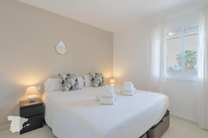 a white bedroom with a large white bed and a window at Zafiro in Calpe