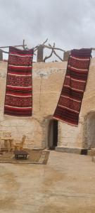 TūjānにあるMaison d'hôte dar massouadaの二枚の絨毯が建物の側に吊るされている