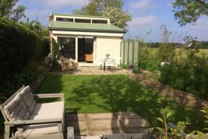 a garden with a white shed with a lawn at Bungalowpark Mooyeveld in Egmond-Binnen