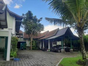 a house with a palm tree next to a driveway at Capital O 93938 Wisma Pamungkas Syariah in Sleman
