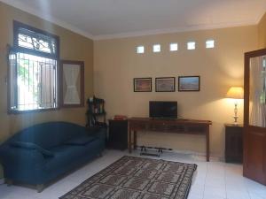 a living room with a blue couch and a desk at Capital O 93938 Wisma Pamungkas Syariah in Sleman