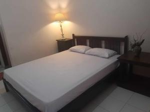 una camera da letto con un grande letto bianco e una lampada di Capital O 93938 Wisma Pamungkas Syariah a Sleman