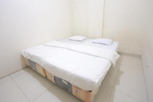 a white bed with two pillows on it in a room at SPOT ON 93827 Rumah Kost Harapan Indah in Bekasi