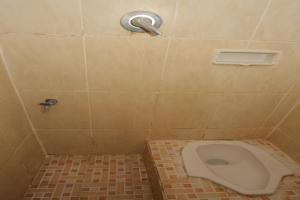 a bathroom with a toilet in a tiled floor at SPOT ON 93908 Angel Guest House in Tangerang