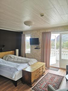 1 dormitorio con 2 camas y TV de pantalla plana en Ulvsvåg Gjestgiveri og Fjordcamping AS, en Ulvsvåg