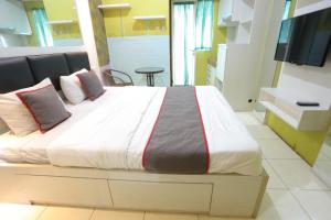 a large bed in a room with a television at Super OYO Capital O 93910 Asia Rooms at Green Lake View Ciputat in Tangerang