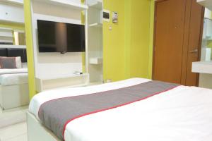 a bedroom with a bed and a flat screen tv at Super OYO Capital O 93910 Asia Rooms at Green Lake View Ciputat in Tangerang