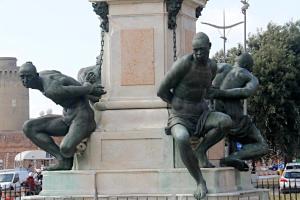 Una statua di tre uomini seduti sopra un monumento di The Port Residence a Livorno