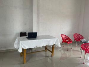 OYO 93947 Bahagia Guest House في ميدان: طاولة عليها جهاز كمبيوتر محمول مع كراسي حمراء