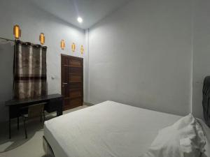 biała sypialnia z łóżkiem i biurkiem w obiekcie OYO 93947 Bahagia Guest House w mieście Medan