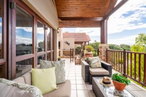 an outdoor patio with wicker furniture and a deck at Luxury , space and views - Pezula Villa 13 in Knysna
