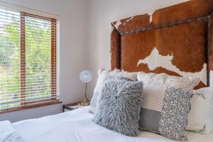 a bedroom with a bed with a wooden headboard and pillows at Luxury , space and views - Pezula Villa 13 in Knysna