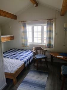 Ulvsvåg的住宿－Ulvsvåg Gjestgiveri og Fjordcamping AS，一间卧室配有一张床、一把椅子和一张书桌