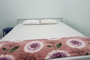 een bed met een witte sprei met paarse bloemen erop bij OYO 93951 Family Guesthouse in Medan