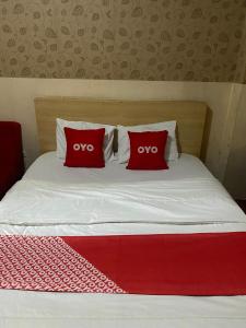 a bed with two red pillows on it at OYO 93952 Dms Property in Bekasi