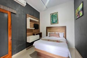een slaapkamer met een bed en een televisie. bij Belvilla 93954 Meta Pandawa Bali Mounth Villa in Jembrana