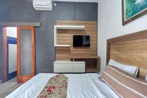 een slaapkamer met een bed en een flatscreen-tv bij Belvilla 93954 Meta Pandawa Bali Mounth Villa in Jembrana