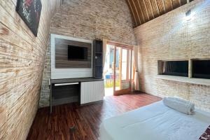 a room with a bed and a flat screen tv at Belvilla 93954 Meta Pandawa Bali Mounth Villa in Jembrana