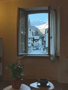 una finestra in una stanza con tavolo e pianta di Casa Smitt ad Alagna Valsesia