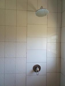 a shower with a white tiled wall and a light at Kulu Lodge Apartments in Lusaka