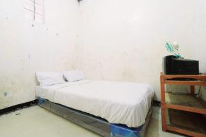 a small bedroom with a bed and a table at SPOT ON 93956 Siliwangi Guest House Syariah in Bandung