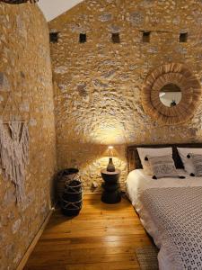 sypialnia z kamienną ścianą z łóżkiem i lampą w obiekcie La Casa Nomade w mieście Issigeac