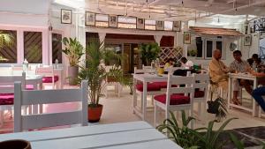 a restaurant with white tables and white chairs and people at Namma Ashram in Bangalore